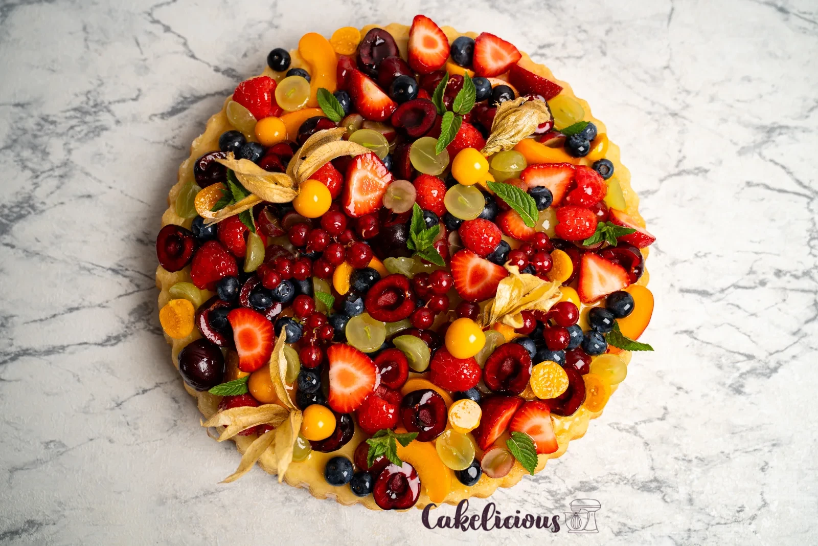 Fruit cake from above, densely topped with berries, apricots and grapes