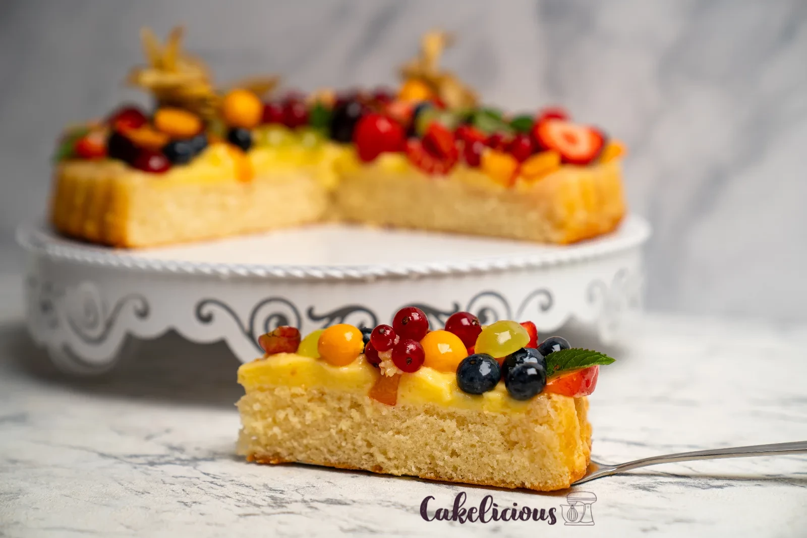 Slice of cake on a dessert plate, with fresh berries in a bowl alongside