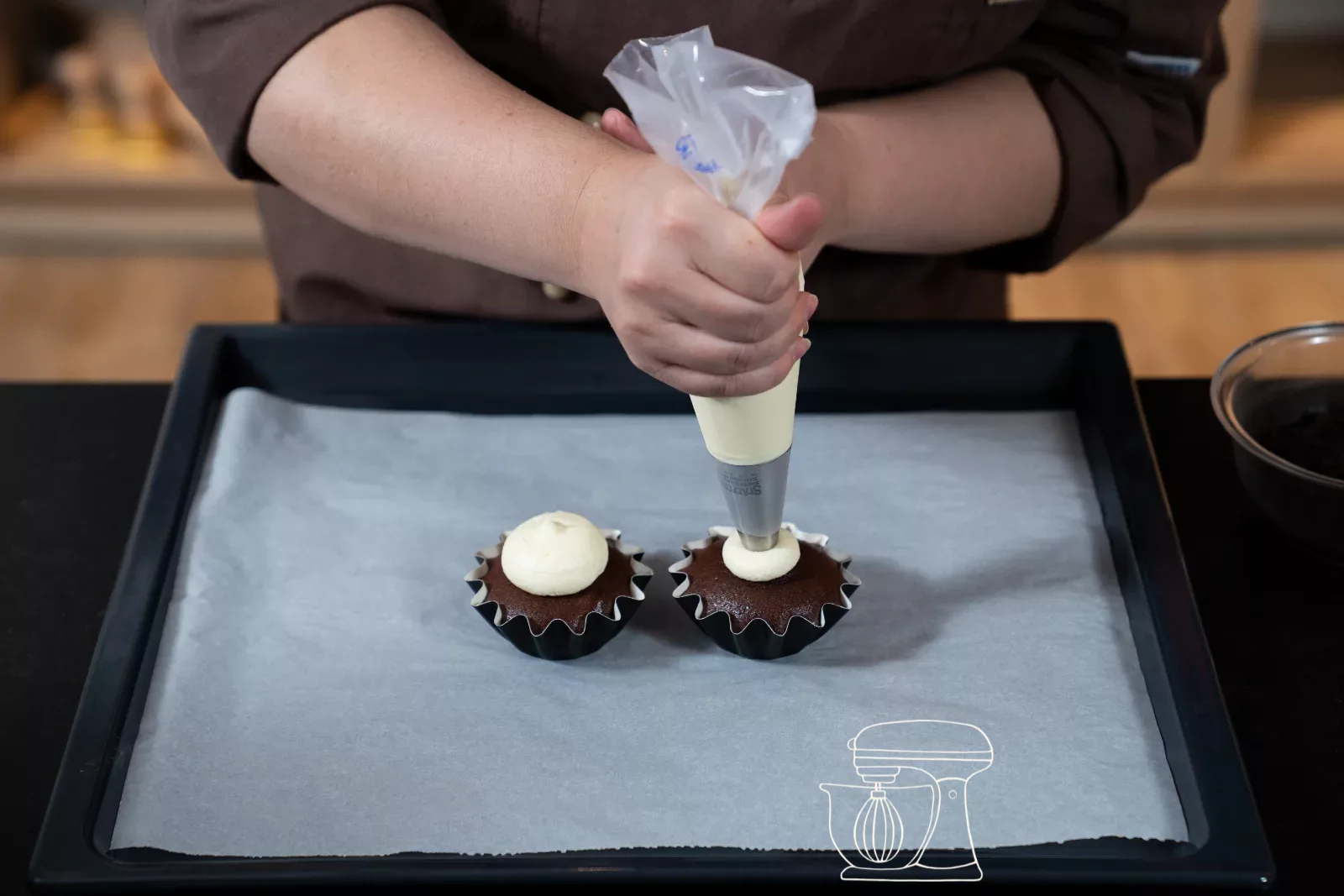 Weisses Frosting wird als hoher Tuff auf einen Cupcake gespritzt