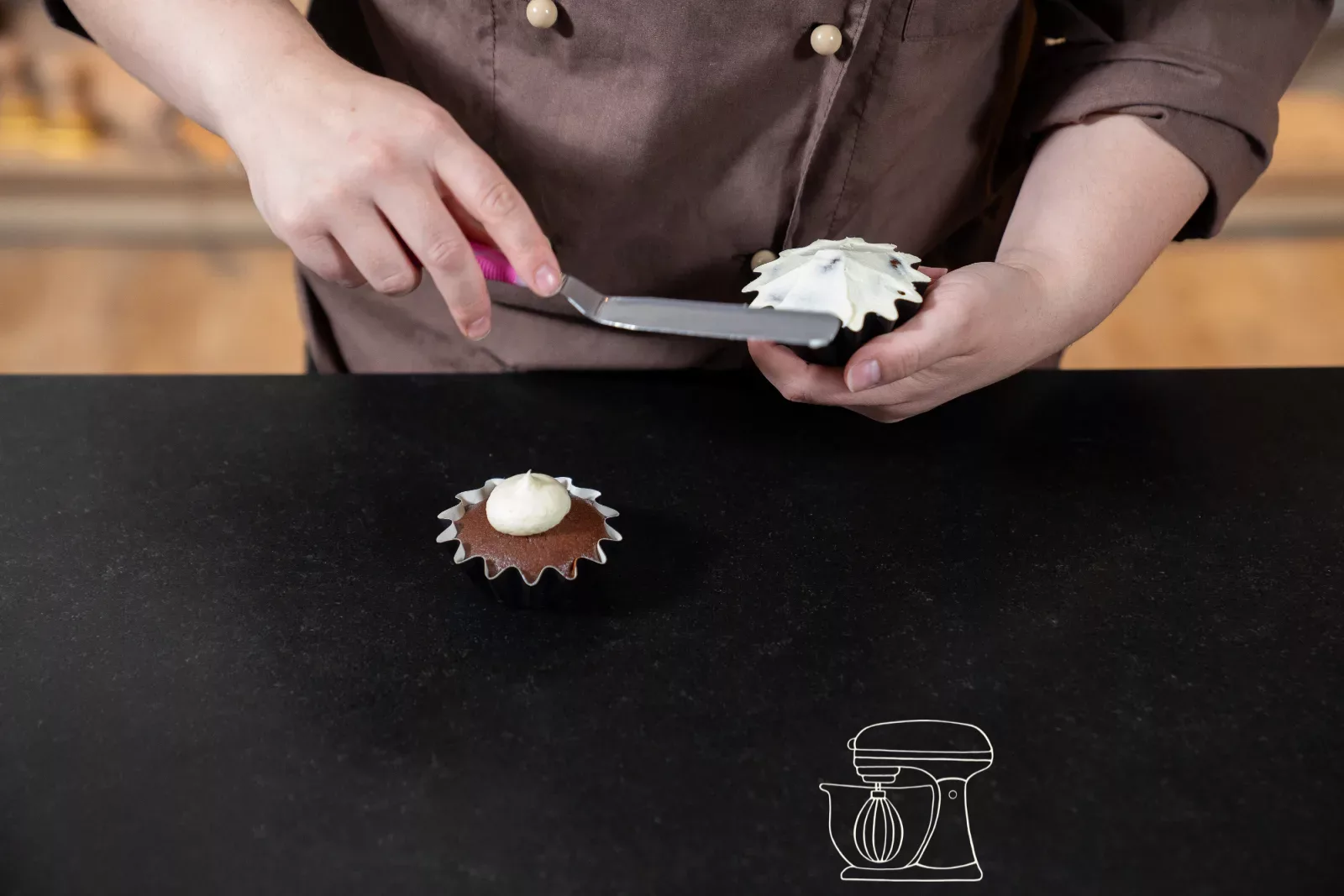 Weisses Frosting wird dünn über den ganzen Cupcake gestrichen