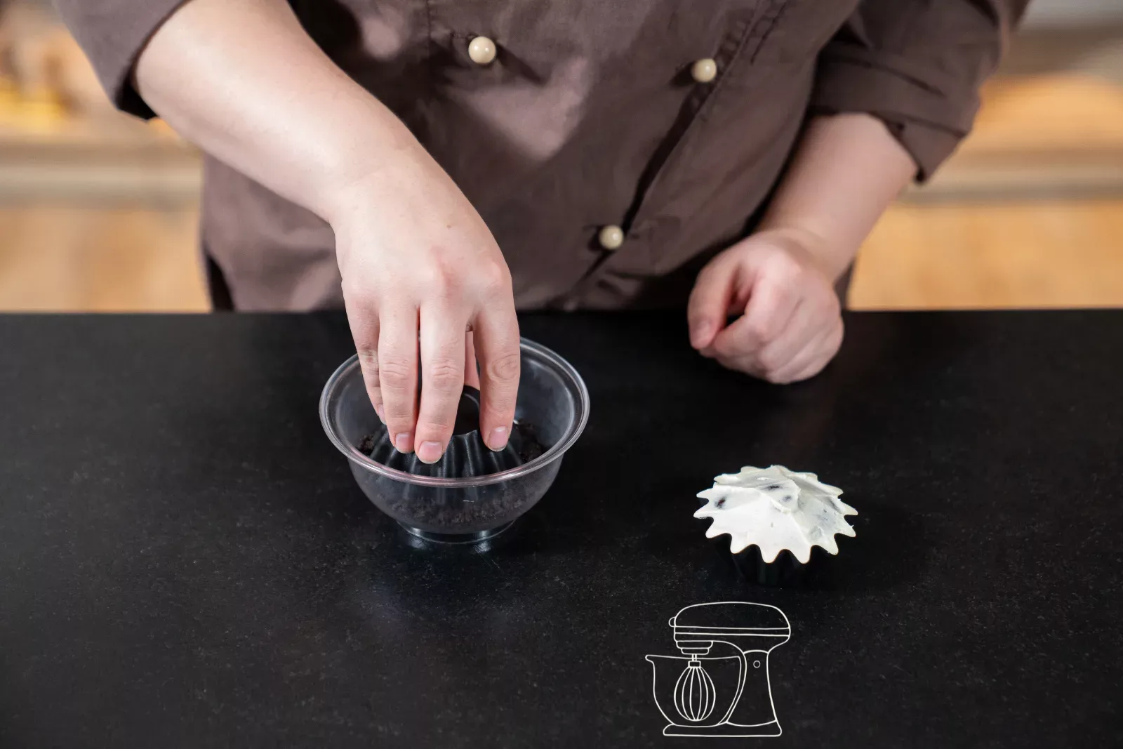 Ein Cupcake wird kopfüber in zerbröselte Oreo getunkt 