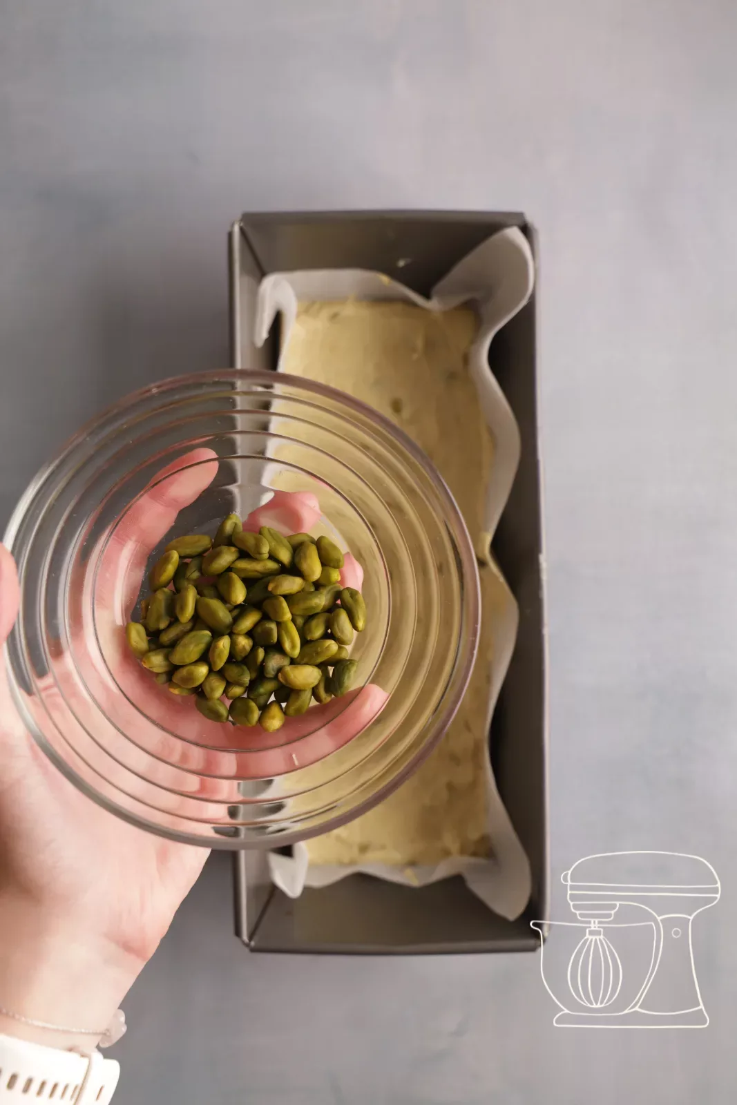 Sprinkling whole pistachios over the batter
