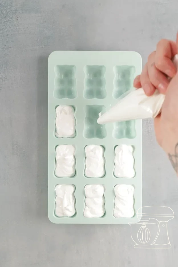 Meringue being piped into the bear silicone mold and smoothed flat