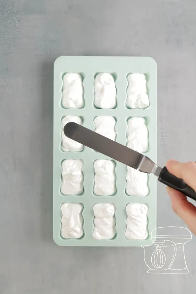 Meringue being piped into the bear silicone mold and smoothed flat