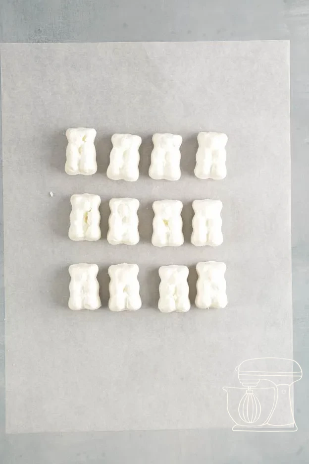 Baked white meringue bears cooling in the silicone mold on the perforated tray