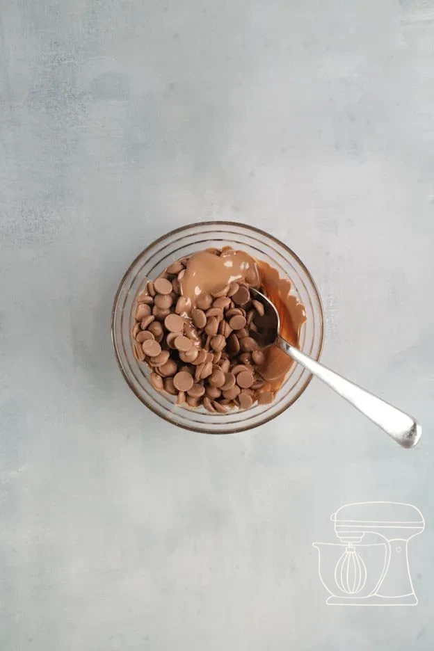 Milk chocolate being melted in a bowl and stirred with the dough scraper