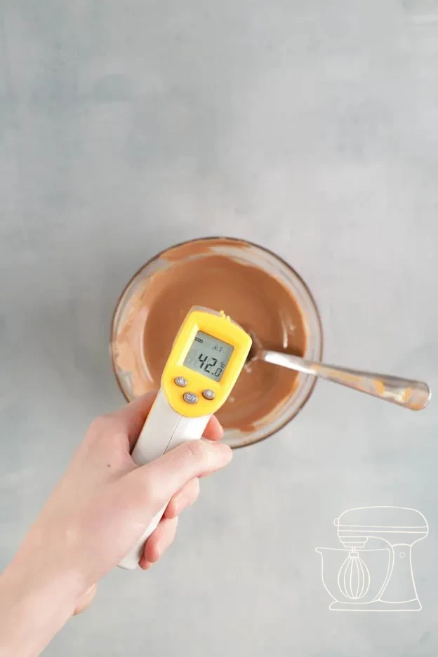 Milk chocolate being melted in a bowl and stirred with the dough scraper