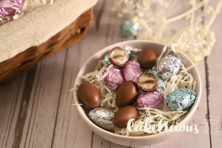 Bonbons au chocolat maison dans un bol avec de la paille de bois, certains enveloppés dans du papier d’aluminium coloré