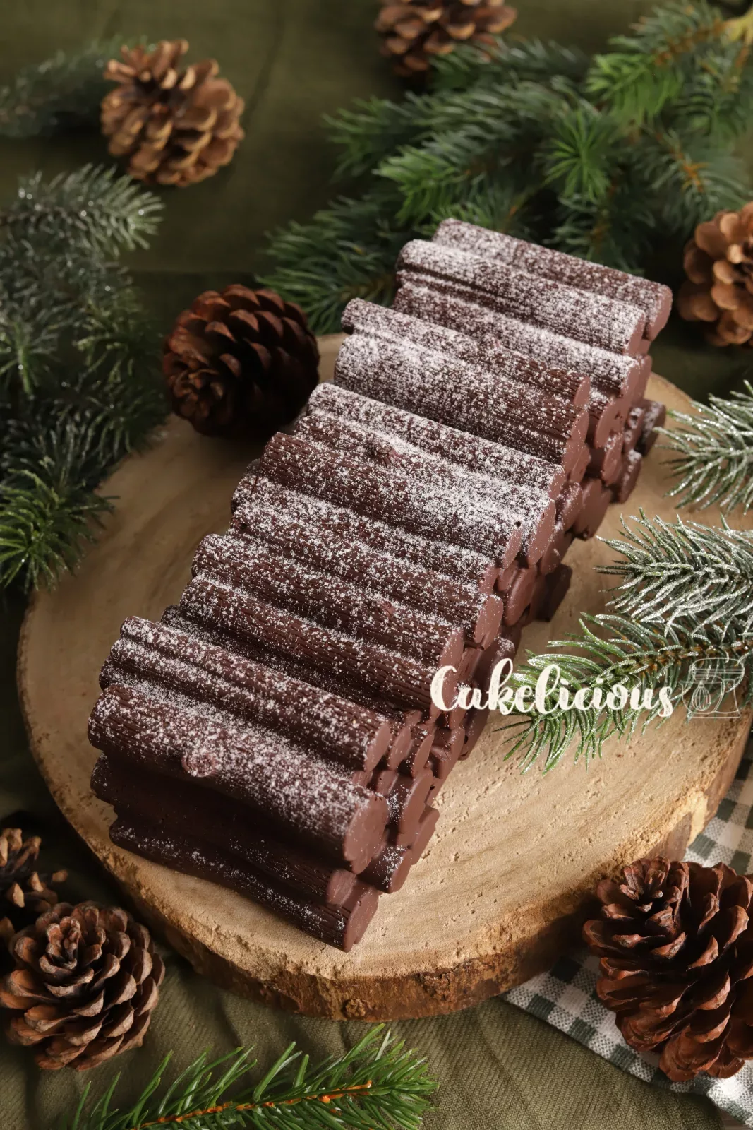 Schoko-Karamell Bûche zwischen Tannenzweigen und Tannenzapfen